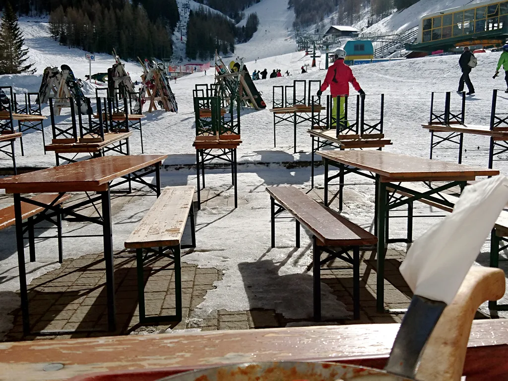 Leere Bierbänke auf der Terrasse einer Skihütte.